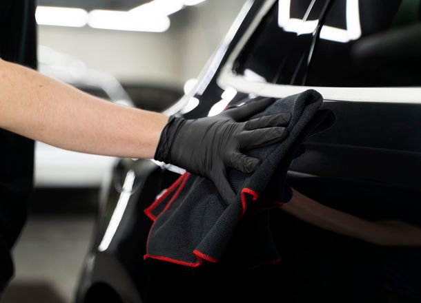 Wiping black car with cloth